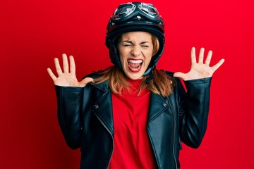 Hispanic young woman wearing motorcycle helmet celebrating mad and crazy for success with arms...