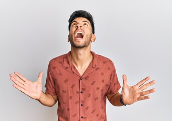 Young handsome man wearing casual summer clothes crazy and mad shouting and yelling with aggressive...