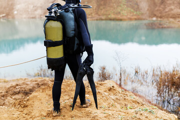 A lifeguard in a wetsuit is preparing to dive into the pond. Search at the bottom of the pond.