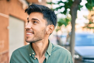 Young latin man smiling happy walking at the city.