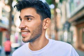 Young latin man smiling happy walking at the city.