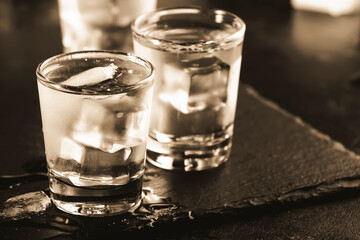 Frozen Vodka in shot glasses on black background, iced strong drink