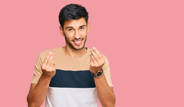 Young handsome man wearing casual clothes doing money gesture with hands, asking for salary payment, millionaire business