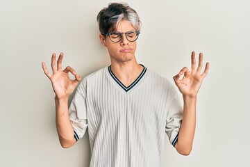 Young hispanic man wearing casual clothes and glasses relax and smiling with eyes closed doing meditation gesture with fingers. yoga concept.