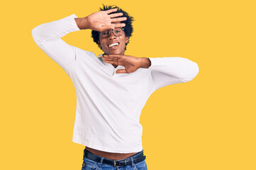 Handsome african american man with afro hair wearing casual clothes and glasses smiling cheerful playing peek a boo with hands showing face. surprised and exited