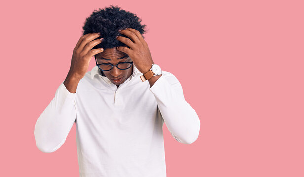 Handsome african american man with afro hair wearing casual clothes and glasses suffering from headache desperate and stressed because pain and migraine. hands on head.