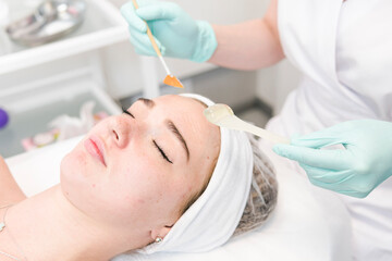 Naklejka premium The young female client of cosmetic salon having a face cleaning procedure. The doctor cosmetologist cleaning skin.