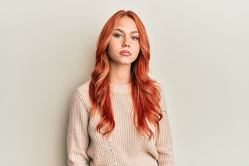 Young beautiful redhead woman wearing casual winter sweater relaxed with serious expression on face. simple and natural looking at the camera.