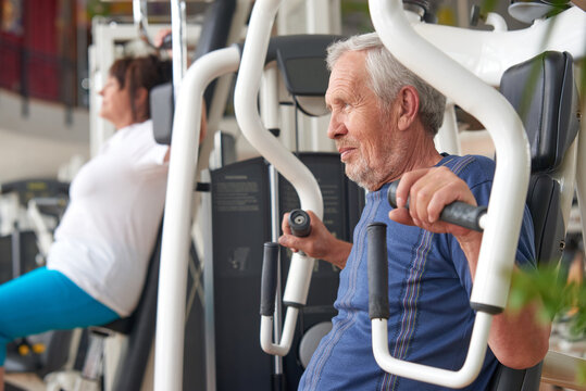 Older Man Doing Strength Exercise At Gym. Mature Man Working Out At Fitness Club. Resistance Exercise At Gym.