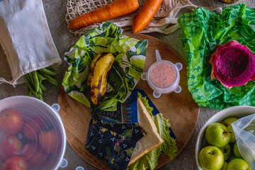 Vegetables, fruits, grains and seeds stored in eco-friendly kitchen packaging: beeswax wraps, reusable ziplock, silicone stretch lids, mesh cotton bags. Zero waste sustainable plastic free lifestyle
