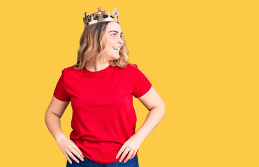 Young caucasian woman wearing princess crown looking away to side with smile on face, natural expression. laughing confident.