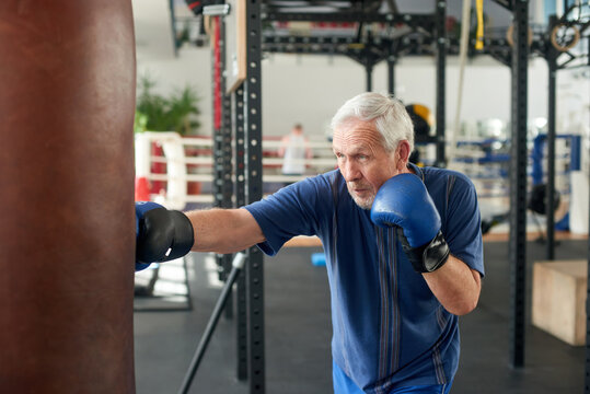 Senior caucasian man training at boxing gym. CBoxing elderly man in boxing room.