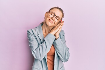 Beautiful caucasian woman wearing business jacket and glasses sleeping tired dreaming and posing with hands together while smiling with closed eyes.