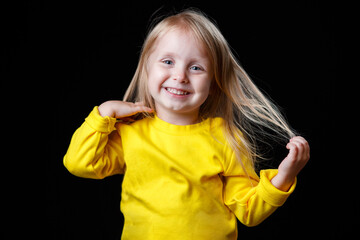 Close-up portrait of a cheerful little girl. Studio shot over dark background. Childhood concept.