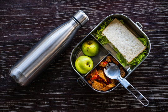 Stainless steel food container or lunch box with healthy vegetarian meal and reusable thermo bottle on wooden background. Eco-friendly kitchen products. Zero waste sustainable plastic free lifestyle