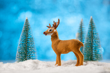 Christmas card. Santa's deer and snowy trees on soft snow on blue background