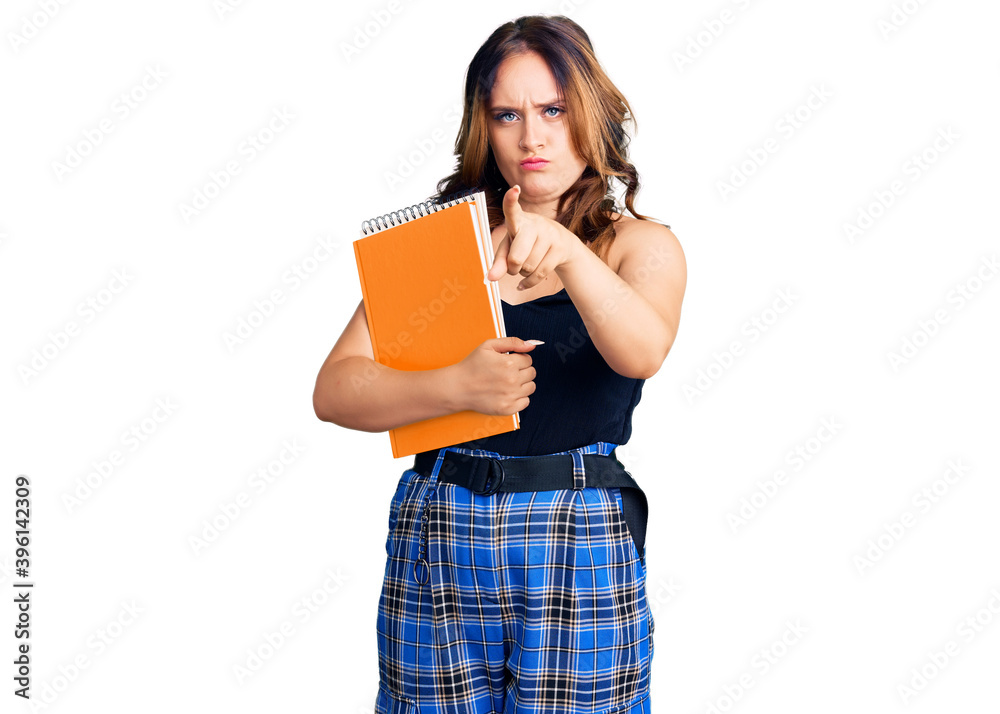 Sticker young beautiful caucasian woman holding book pointing with finger to the camera and to you, confiden