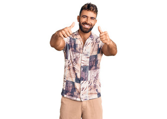 Fototapeta premium Young hispanic man wearing summer clothes approving doing positive gesture with hand, thumbs up smiling and happy for success. winner gesture.