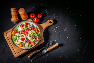 Healthy vegetable salad of fresh tomato, green leaves mix and vegetables. Top view on dark bacground. Diet menu