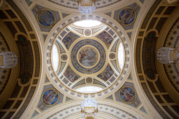 Fototapeta premium A bottom-up view of the interior of a big building. Brightly lit dome with semicircular windows and religious paintings
