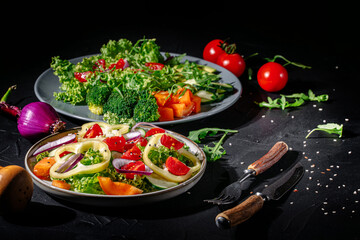 Healthy vegetable salad of fresh tomato, green leaves mix and vegetables. Top view on dark bacground. Diet menu