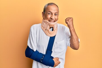 Handsome mature senior man wearing cervical collar and arm on sling very happy and excited doing...