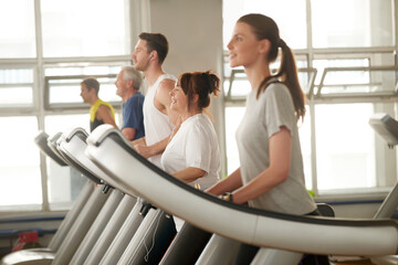 Obraz premium People on treadmill at gym. Cheerful mature woman using treadmill machine at fitness club. It is never too late to improve your health.