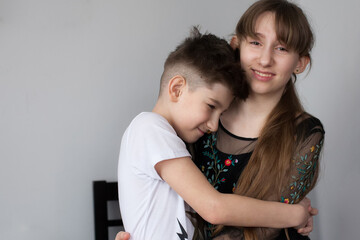 Brother and sister hugging each other. Pretty girl and young boy cuddling. Puppy love, relationships and childhood. Happy family