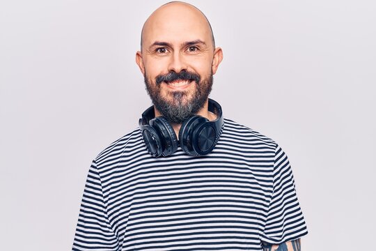 Young handsome man listening to music using headphones with a happy and cool smile on face. lucky person.