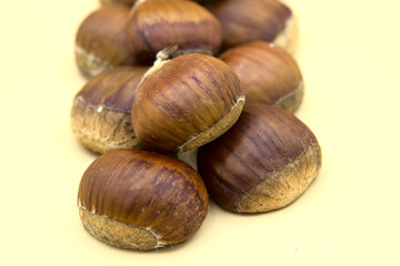 In the foreground on a white background a group of chestnuts. The basis of autumn cuisine.