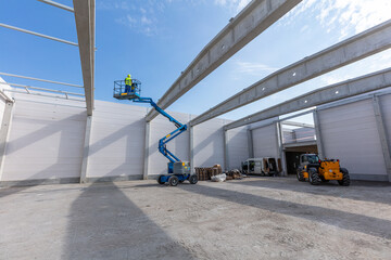 Warehouse construction. Worker on mobile elavating work platform