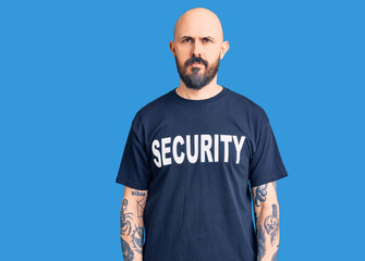 Young handsome man wearing security t shirt relaxed with serious expression on face. simple and natural looking at the camera.