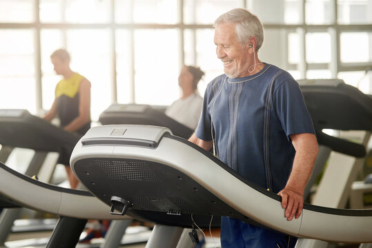 Smiling senior man on treadmill at gym. Male pensioner exercising at fitness club. Morning workout at gym. - Powered by Adobe