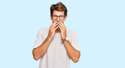 Handsome caucasian man wearing casual clothes and glasses laughing and embarrassed giggle covering...