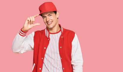 Handsome caucasian man wearing baseball uniform smiling and confident gesturing with hand doing small size sign with fingers looking and the camera. measure concept.