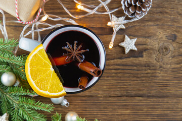 Top view of Christmas and New Year's drink hot wine, mulled wine, punch or tea on wooden background next to green Christmas tree and garland. Place for text