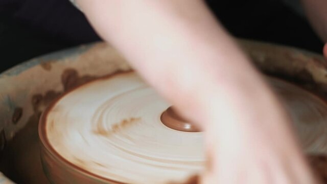 hands working clay on potter's wheel. Potter shapes the clay product with pottery tools on the potter's wheel, craft factory authentic. Close up. 4k