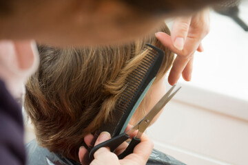 mujer cortando el pelo con tijera a niño 