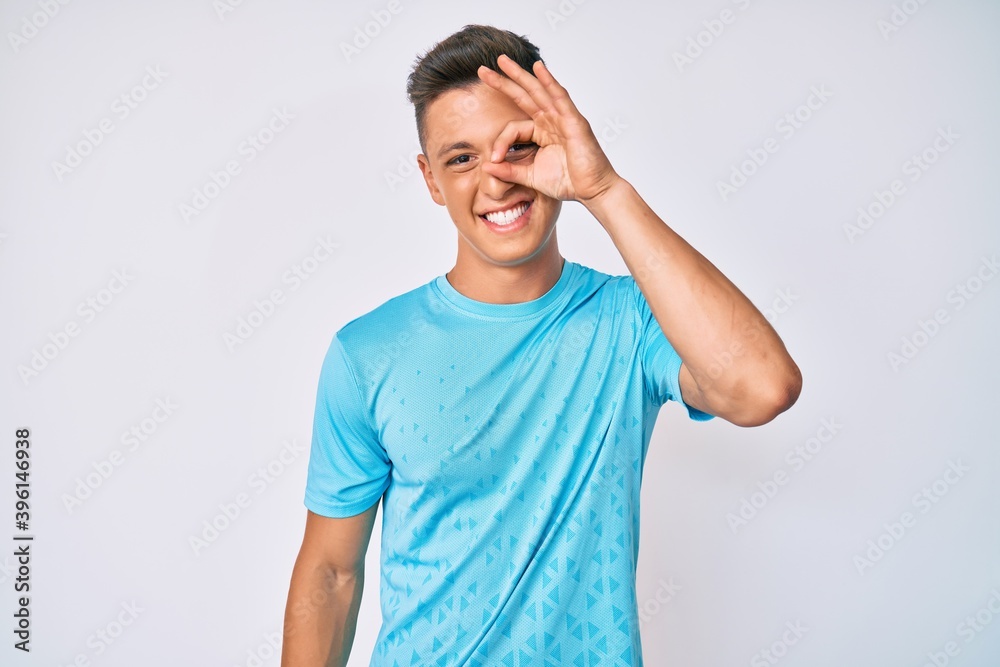 Wall mural Young hispanic boy wearing casual clothes smiling happy doing ok sign with hand on eye looking through fingers