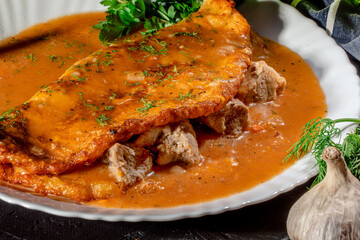 Potato pancakes with meat, vegetable, tomato and parsley on dark background