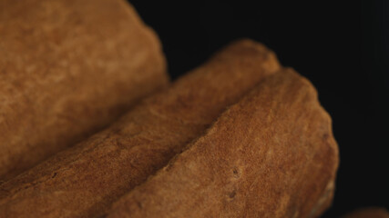 Cinnamon sticks on a dark background.  Spicy cinnamon seasoning for baked goods, fruit desserts, puddings and drinks. Extreme close-up, macro view