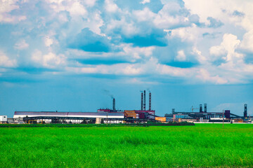 Fototapeta na wymiar Fumes of a mining plant against the sky and green grass.