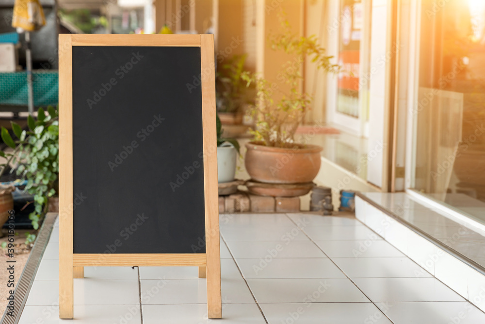 Wall mural Wooden rustic blackboard in front of restaurant entrance. Mock up Menu Blank Blackboard sign stand Shop Cafe Restaurant. Street Magnetic Sidewalk Chalkboard.