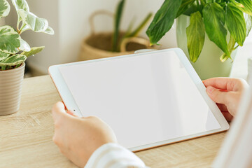 Horizontal tablet mockup held by a woman who is in the living room. White screen