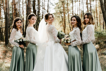 beautiful young bride stands with bridesmaids holding a wedding bouquet with flowers, beautiful...