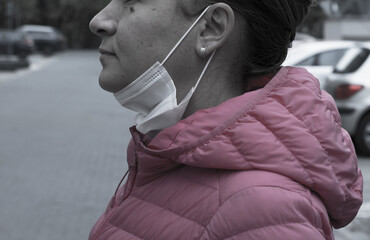 Woman casually wearing a medical protective mask under her chin. Improper use of a mask. 