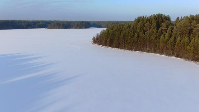 Flight over a taiga forest lake in winter