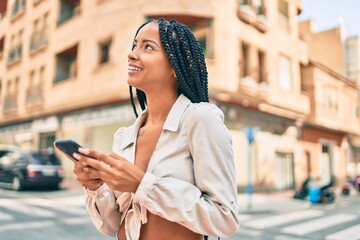 Young african american woman smiling happy using smartphone at the city.