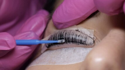 Face of young girl before eyelash lamination procedure in a professional beauty salon. The master washes off the black paint on the eyelashes during the eyelash curling procedure with a special brush.