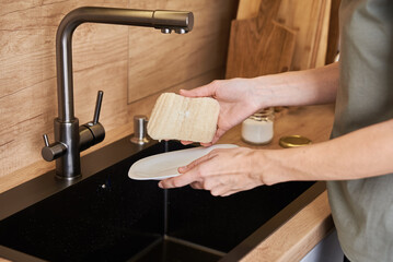 Woman wash dishes with organic eco friendly sponge. Zero waste concept - obrazy, fototapety, plakaty